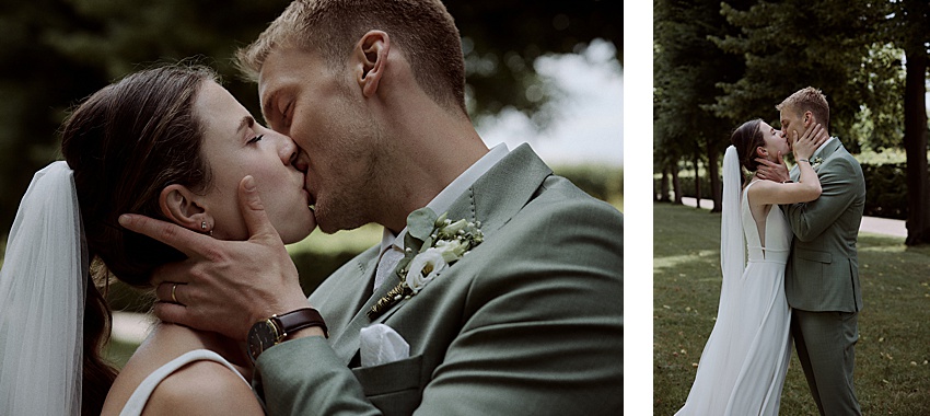 Ein Paar im Hochzeitskleid küsst sich draußen in den Herrenhäuser Gärten. Der Bräutigam trägt einen hellgrünen Anzug mit Ansteckblume und die Braut ein weißes Kleid mit Schleier. Sie stehen auf Gras, umgeben von Bäumen, und fangen die Atmosphäre ihrer Standesamtlichen Hochzeit in Hannover ein.